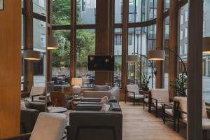 a lobby with chairs and tables and windows at Zenit San Sebastián in San Sebastián