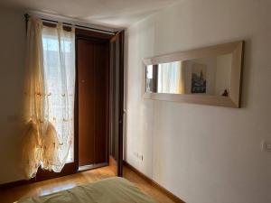 1 dormitorio con ventana y espejo en la pared en Affittacamere La Casa Gialla, en Remanzacco