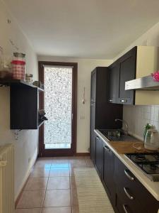 una cocina con armarios negros y una gran ventana en Affittacamere La Casa Gialla, en Remanzacco