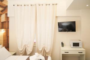 Napolitano Rooms (Central Station) في نابولي: غرفة نوم مع ستارة بيضاء وتلفزيون