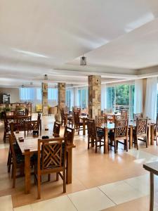 un restaurante con mesas y sillas de madera y ventanas en The Address Resort en Kalangala
