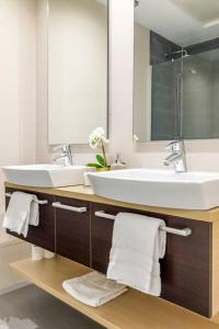 a bathroom with two sinks and a mirror and towels at JA Suites Madrid in Madrid