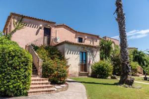 a house with stairs and a palm tree at Apartments in residence with swimming pool in Santa Margherita di Pula, 250 meters from the sea in Pula