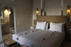 Un dormitorio con una gran cama blanca con pájaros. en Riad Emberiza Sahari, en Marrakech