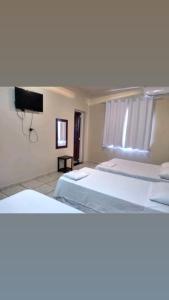 a bedroom with two beds and a flat screen tv at HOTEL VEREDAS in Monsenhor Paulo