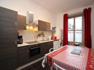 eine Küche mit einem Tisch und einem roten Tischtuch in der Unterkunft Appartement T3 au Mont-Dore, Centre, 3 étoiles, balcon, ascenseur, WIFI, proche Thermes et navette ski - FR-1-608-17 in Le Mont-Dore