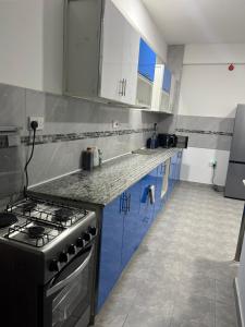 a kitchen with blue cabinets and a stove top oven at Fortune Zone in Dar es Salaam
