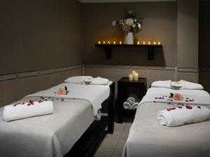 a room with three beds with white towels and flowers on them at Delta Hotels by Marriott Manchester Airport in Hale