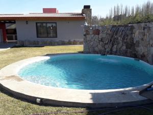 una gran piscina con una pared de piedra y una fuente de agua en Quality time en Luján de Cuyo