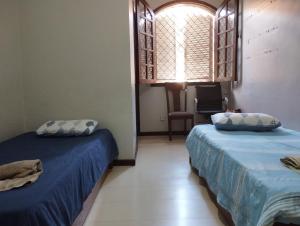 two beds in a room with a window at Retiro Luxuoso:Casa Espaçosa com Piscina Privativa in Campos dos Goytacazes