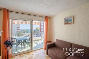 a living room with a couch and a balcony with a table at Apartamento Rosmarin by MarCalma in Miami Platja