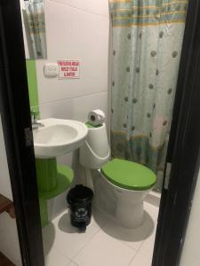 baño con aseo verde y lavamanos en Hotel La Fresa en Pereira