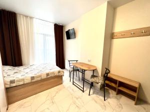 um quarto com uma cama, uma mesa e uma janela em Apart Hotel in a complex Semycvit em Lviv