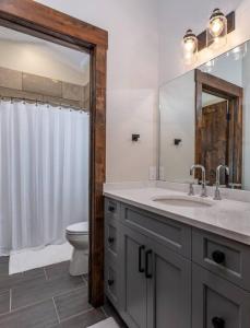 y baño con lavabo, aseo y espejo. en Beautiful 5 BR Wild Mustang Home in Victor, ID, en Victor