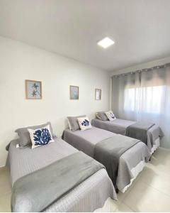 a bedroom with three beds in a room at TULUM Bertioga - belo apartamento com vista para o mar in Bertioga