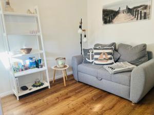 uma sala de estar com um sofá cinzento e prateleiras brancas em SeeLund - Meeresrauschen lauschen - ruhiges sonniges Apartment mit Garten und Terrasse nahe Strand und Ostsee em Schönhagen