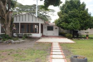 a white house with a tree in the yard at VILLA ALEJANDRIA - CABAÑA LAMARIQUITA-CABAÑA ORQUIDEA-CABAÑA CARAMBOLa in Mariquita