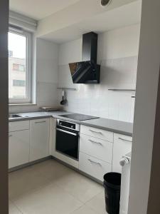 a kitchen with white cabinets and a black oven at airport cybernetyki2 inn in Warsaw
