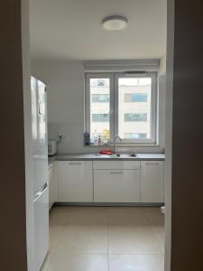 a white kitchen with a sink and a window at airport cybernetyki2 inn in Warsaw +7 photos