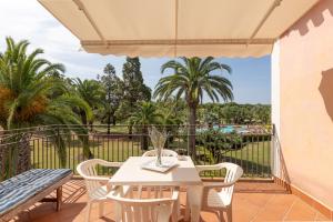 a white table and chairs on a balcony with palm trees at ISA-Residence with swimming-pool in Santa Margherita di Pula, apartments with air conditioning and private outdoor space at only 250 m from the beach in Santa Margherita di Pula