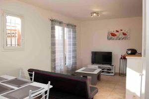 Una sala de estar con un sofá y un televisor. en Gîte les coquelicots 2 Quartier résidentiel ( 2 * ), en LʼIsle-sur-la-Sorgue