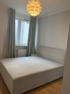 a bed in a room with a window and a chandelier at airport cybernetyki2 inn in Warsaw