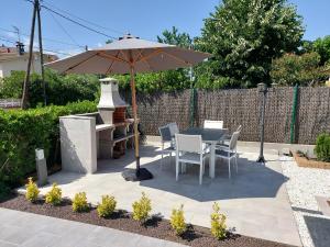 un patio con sombrilla, mesa y sillas en Casa parque Natural Montseny con piscina, barbacoa y Chimenea, en Sant Antoni de Vilamajor