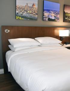 um quarto com uma cama branca e duas fotografias na parede em Delta Hotels by Marriott Indianapolis East em Indianápolis