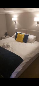 a white bed with two pillows and a yellow pillow at The Red Lion Great Offley in Great Offley