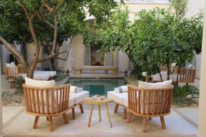 um pátio com 2 cadeiras, um sofá e uma piscina em Riad Emberiza Sahari em Marraquexe