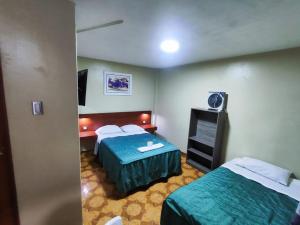 una camera d'albergo con due letti e una televisione di Hostal Continental a Nazca Altre 10 foto