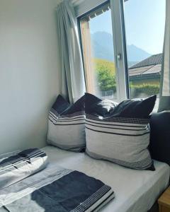 asiento junto a la ventana con almohadas frente a una ventana en Bergpanorama Lodge — Alpenidylle, en Thaur