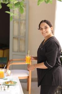 una mujer sosteniendo un vaso de jugo de naranja en Riad Emberiza Sahari, en Marrakech