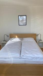 a bed with white sheets and two lamps on two tables at Wohnung am Spitalberg in Klagenfurt