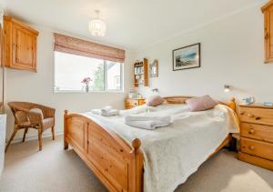 a bedroom with a bed and a chair and a window at Curlews Trevone in Padstow