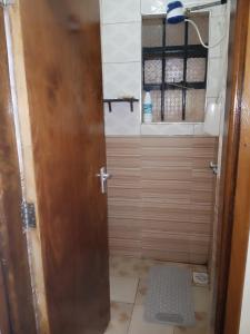 CeeJ'S Airbnb في Meru: دش مع باب خشبي في الحمام
