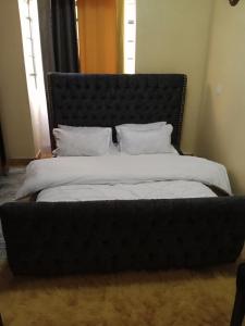 CeeJ'S Airbnb في Meru: سرير كبير مع اللوح الأمامي الأسود في غرفة النوم