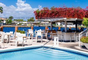 uma piscina com mesas e cadeiras junto à água em Sands Harbor Resort and Marina em Pompano Beach