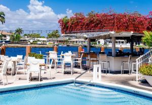 a pool with tables and chairs next to the water at Sands Harbor Resort and Marina in Pompano Beach