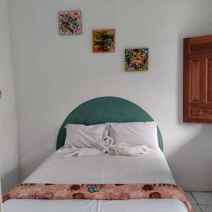 a bed with a green headboard and three pictures on the wall at João de Barro Hospedagem in Caeté-Açu