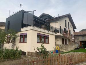 une grande maison blanche avec un toit noir dans l'établissement B&B Kalbermatter, à Turtmann