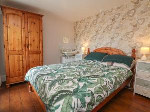 a bedroom with a bed with a green and white bedspread at Tea Cosy Cottage in Bude