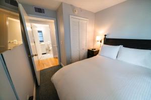 a bedroom with a large white bed and a bathroom at Sandpiper Beach Club in Cape May