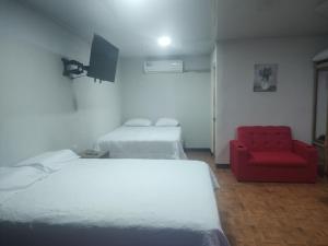 Habitación con 2 camas y silla roja. en Villas El Alto 1, en Tambor
