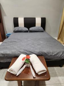 a bed with two white towels on a wooden table at Galaxy Guest Home by Ipoh Maju Stay in Ipoh