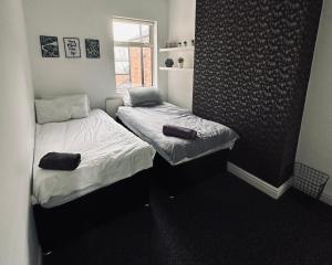 two twin beds in a room with a window at Spacious 4 Bedrooms, 3 Bathrooms, Sleeps 8 in Coventry