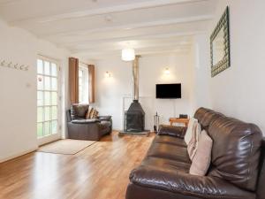 a living room with a leather couch and a fireplace at Bracken Cottage in Bodmin