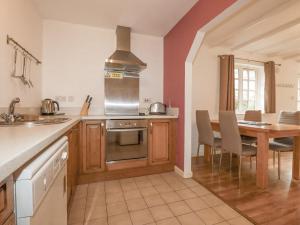 a kitchen with a stove and a table with chairs at Bracken Cottage in Bodmin