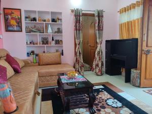 sala de estar con sofá y TV en Vrindavan, en Mysore
