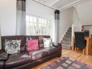 a living room with a brown leather couch at Nest Cottage in Bodmin